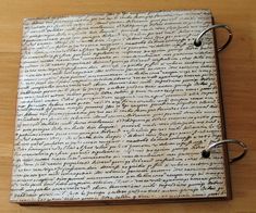 an old book with writing on it sitting on a wooden table next to a pair of scissors