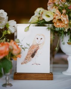 an owl is sitting on top of a card next to some flowers and vases