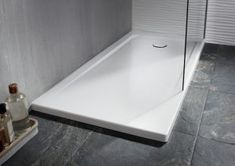 a white bath tub sitting on top of a stone floor next to a shower head