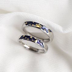 two rings with sun and moon designs on them sitting on a white cloth covered surface