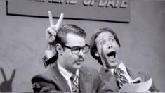 two men in suits and ties making the v sign with their hands while standing next to each other