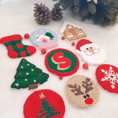 crocheted christmas ornaments are arranged on a white surface next to a pine tree