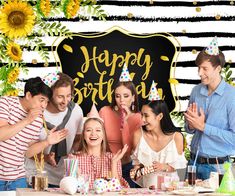 a group of people standing in front of a table with cake and candles on it