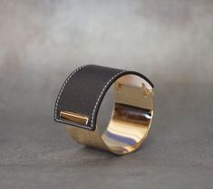 "i t e m ∙ d e t a i l s Crafted with high quality Saffiano leather and silver plated brass. The leather is hard wearing, practical and easy to wipe clean. This bracelet is finished with an exquisite stitch, creating a delicate detail. Solid metal cuff adds chic and bold style to your look. Easy to wear, it wraps tight around your wrist. *Click any color in 'Color' section. It is linked with photos of that specific color. d i m e n s i o n s L - 7.25\" (18.4cm) , W - 1.5\" (3.8cm) Inner Circumfe Elegant Brown Cuff Bracelet As Gift, Elegant Brown Cuff Bracelet Gift, Formal Gold Leather Cuff Bracelet, Designer Black Cuff Bracelet For Formal Occasions, Gold Leather Cuff Bracelet, Gold Leather Cuff Bracelet For Formal Occasions, Chic Cuff Jewelry For Evening, Chic Evening Cuff Jewelry, Chic Cuff Bracelet For Evening