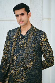 Black silk open jacket with all over contrast gold figurine, tree print and bead embroidered lapel collar. Paired with printed straight kurta and contrast trousers.
Components: 3
Pattern: Printed and Embroidered
Type Of Work: Figurine, Tree Print and Bead Work
Neckline: Jacket: Lapel Collar, Kurta: Mandarin Collar
Sleeve Type: Full Sleeves
Fabric: 100% Silk
Color: Black,Gold
Other Details: 
Curved kurta hem
Kurta Closure: Front buttons
Occasion: Sangeet,Cocktail and Reception - Aza Fashions Traditional Gold Semi-formal Sets, Formal Suits With Printed Motifs And Long Sleeves, Silk Sets With Printed Motifs For Formal Occasions, Elegant Formal Suit With Printed Motifs, Festive Semi-formal Silk Suits, Elegant Traditional Wear With Printed Motifs For Formal Occasions, Elegant Traditional Wear With Printed Motifs For Formal Events, Elegant Formal Traditional Wear With Printed Motifs, Festive Long Sleeve Suits With Gold Embroidery