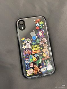 an iphone case with various stickers on it sitting on top of a gray surface