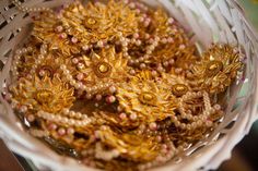 a basket filled with lots of gold colored beads