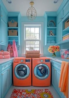 a washer and dryer in a small room with blue cabinets, pink rugs and flowers on the floor