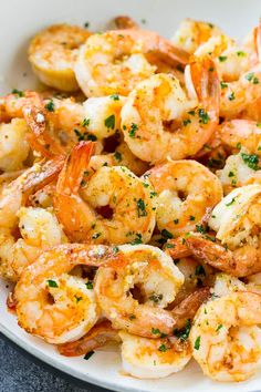 a white bowl filled with cooked shrimp and garnished with parsley