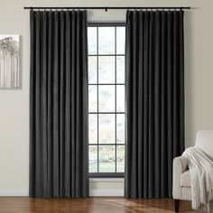 the black curtains are hanging in front of a window with wood floors and white walls