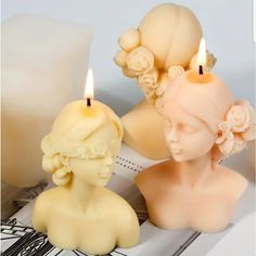 two candles are sitting next to each other on top of a piece of paper with an image of a woman's head