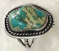 "Vintage 1980's Cerrillos Turquoise Stone Ring With Sterling Silver Bezel And Oxidised Rope With Double Band Beaded Detailing  Size 10 1/2  Southwestern Artisan Signed  T Mc   (Tom McAuliffe) Ring Size  10 1/4 Length:  1 3/8\"    ( 35mm)  Width:   1\"   (25mm ) Height:  1 1/4\"  (32mm ) includes band Weight:    .6oz Cerrillos Turquoise Gemstone Length:    1\"  ( 25mm) Width:     3/4\"  ( 19mm)  Height:  1/4\"   ( 6mm)   The Cerrillos turquoise mines which are Ancestral Puebloan mines that has be Vintage Oval Turquoise Ring, Collectible Green Turquoise Ring, Turquoise Stone Ring, Size 10 Rings, Turquoise Gemstone, Ring Sterling Silver, Stone Ring, Turquoise Stone, Rings Statement