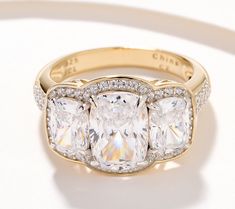 a three stone ring with diamond accents on the sides and an oval center surrounded by smaller round diamonds