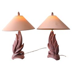 two lamps that are sitting side by side on a white surface, one has a light shade and the other has a leaf design