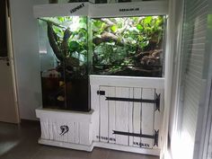 a fish tank sitting on top of a window sill next to a wall with plants in it