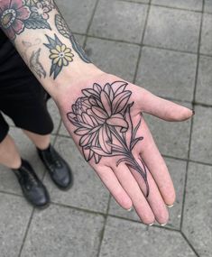 a person's hand with a flower tattoo on it