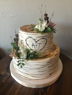 a three tiered cake decorated with flowers and leaves on top of a wooden table