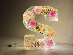 the letter s is made out of glass with flowers and leaves on it's sides