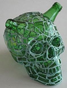 a green glass skull head with a bottle in it's mouth