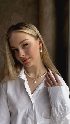 a woman wearing a white shirt and pearl necklace