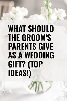 a vase filled with white flowers sitting on top of a table next to a sign that says, what should the groom's parents give as a wedding gift top ideas?