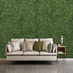 a couch sitting in front of a wall covered in green grass covering it's walls