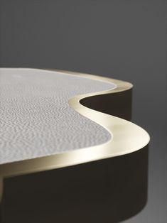 a close up view of a white table with curved edges and gold trimmings