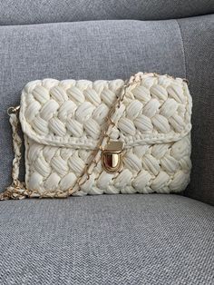 a white purse sitting on top of a gray couch