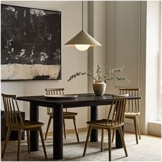 a dining room table with chairs and a vase on the table in front of it