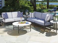 an outdoor living area with couches and tables next to a swimming pool in the background