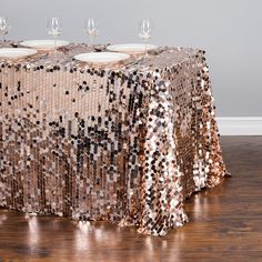 a table covered in sequins with wine glasses sitting on top of the table