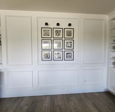 an empty room with white walls and pictures on the wall, along with wooden flooring