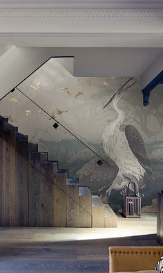 a large bird painted on the side of a wall next to a stair case in a living room