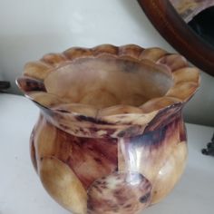 a brown and white vase sitting on top of a table next to a mirror,