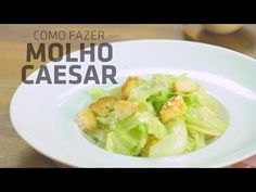 a white plate topped with lettuce and croutons on top of a wooden table