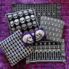 three pillows with skulls on them are sitting on a purple and black rug next to each other