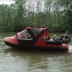 a red and black boat in the water with a canopy on it's back