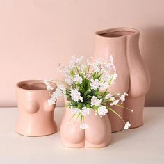 three pink vases with white flowers in them