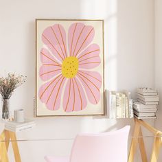 a pink chair sitting in front of a painting on the wall next to a table