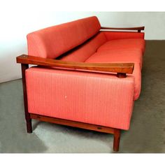 an orange couch sitting on top of a floor next to a wooden frame and arm rest