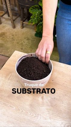 a person scooping dirt into a bowl on top of a wooden table with the words truque do substrato above it