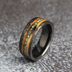 a wedding ring with wood inlays and green, yellow and black stripes on it