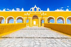 a yellow building with arches and pillars on the outside, surrounded by cobblestones