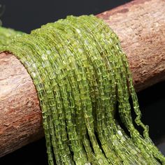 some green beads are sitting on top of a piece of wood