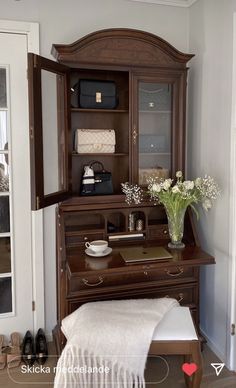 a wooden desk with flowers in a vase on top of it and a mirror above it