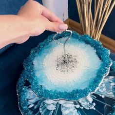 a person is decorating a blue and white plate with silver decorations on it's rim