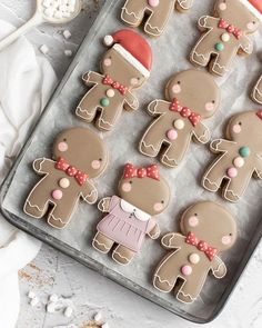 decorated gingerbreads in the shape of people on a baking sheet with spoon and utensils