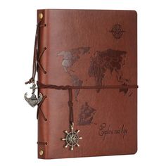 a brown leather journal with world map and compass charms on the front, tied to an elastic band