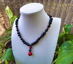 A striking bohemian gemstone and wood bead necklace; crafted with painted black wood beading, black pressed Czech glass beading, matte black agate stone, polished mahogany obsidian stone, and a handmade stone pendant with earthy polished tree agate stone, polished red tourmaline stone, and polished red coral stone. *Handmade by me, one of a kind. *Hypoallergenic stainless steel chain and clasp.  Nickel Free. *Total Length: 18 inches *Length of Chain: 15 inches *Extender Length: 2 inches. If you require a longer extension chain to ensure a proper fit, please let me know!  Just let me know how long you would like your extension chain under personalization instructions. (free of charge) *Diameter of Coral Stone: 12 mm *Pendant Length: 3 cm *Clasp and Chain Material: Lobster claw and jump ring Artisan Black Necklaces With 8mm Beads, Black Wooden Beaded Necklaces For Festival, Black Wooden Beads Necklace For Festival, Black Wooden Beaded Necklace For Festivals, Black Necklaces With Wooden Beads For Healing, Artisan Black Necklace With 8mm Beads, Red Gemstone Beaded Bohemian Necklace, Handmade Bohemian Lava Stone Jewelry, Whimsigoth Jewelry