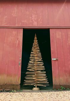 a wooden christmas tree in front of a red barn